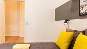 Un dormitorio con una cama, una lámpara de noche y una puerta que da a otra habitación.
