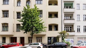 Un immeuble à plusieurs étages, doté d’une façade symétrique, de nombreux balcons et d’un arbre devant.