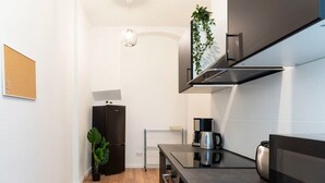 Une cuisine moderne équipée d’un réfrigérateur noir, d’une machine à café et d’un téléviseur à écran plat.
