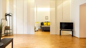 Un salon moderne avec un plancher en bois, un canapé avec des coussins jaunes, un téléviseur posé sur un meuble et un placard à portes coulissantes.