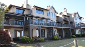 A multi-story residential building with balconies, a covered patio area, and a well-maintained lawn. - Waterfront living at Bohicket Marina, spacious 3BR townhome in Seabrook Island! No Pets Allowed. (Seabrook Island)
