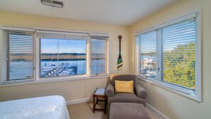 A bedroom with a bed, a sofa, and a view of a marina through large windows. - Waterfront living at Bohicket Marina, spacious 3BR townhome in Seabrook Island! No Pets Allowed. (Seabrook Island)
