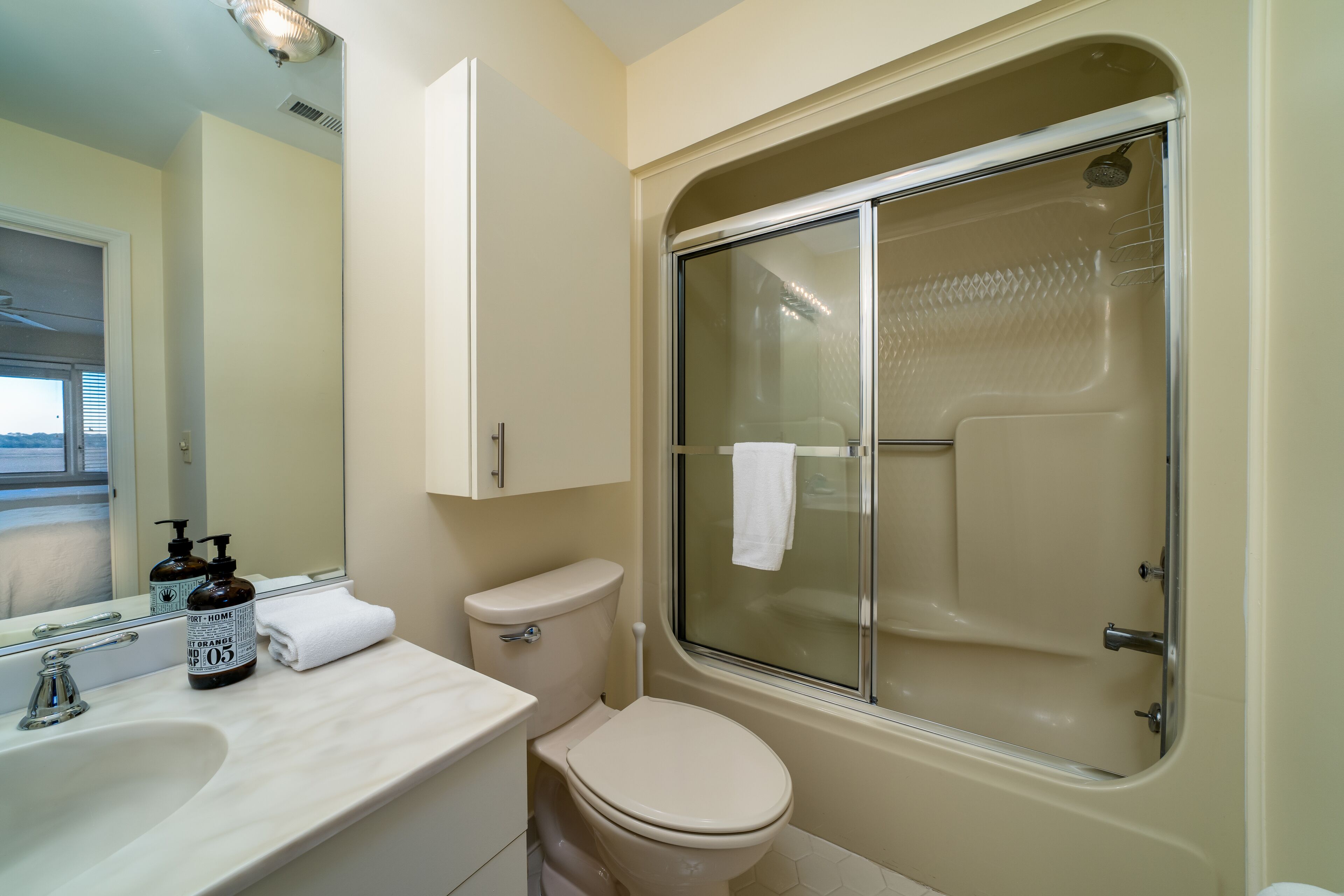 Une salle de bain comprenant des toilettes, un lavabo, un miroir et une cabine de douche.