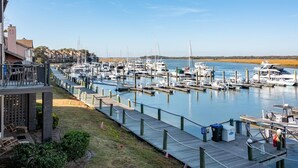 A marina with multiple docks and boats, a wooden walkway, and a building with outdoor seating. - Waterfront living at Bohicket Marina, spacious 3BR townhome in Seabrook Island! No Pets Allowed. (Seabrook Island)