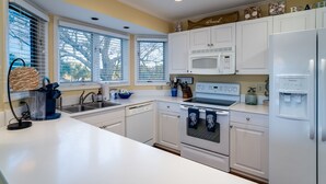 A modern kitchen with white cabinets, a built-in microwave, and a refrigerator. - Waterfront living at Bohicket Marina, spacious 3BR townhome in Seabrook Island! No Pets Allowed. (Seabrook Island)