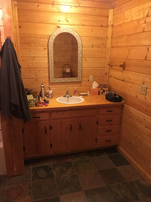 A wooden cabin bathroom with a sink, mirror, and cabinets. - Private mountain Property, end of the road Privacy (Ellijay)