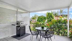 Eine Terrassengruppe mit Grill, rundem Tisch und Stühlen.