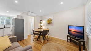 Cozy living space with a dining area, sofa, flat-screen TV, and kitchenette.