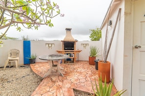 A patio with a brick oven, a round table, and potted plants.