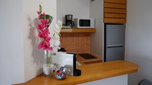 A kitchen with a microwave, coffee maker, and refrigerator. - Cozy single bedroom apartment with pool and private beach (Saint-François)