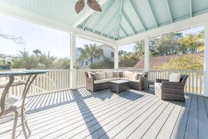 Terraza cubierta al aire libre con mobiliario de mimbre y una mesa.