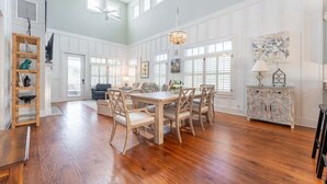 A spacious dining area with a wooden table and chairs, a chandelier, and a white cabinet with drawers. - Walk-to-Beach Luxury Coastal Home Near Pier Village, St. Simons Island (St. Simons Island)
