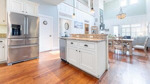 A spacious kitchen with white cabinetry, stainless steel appliances, and a large island. - Walk-to-Beach Luxury Coastal Home Near Pier Village, St. Simons Island (St. Simons Island)