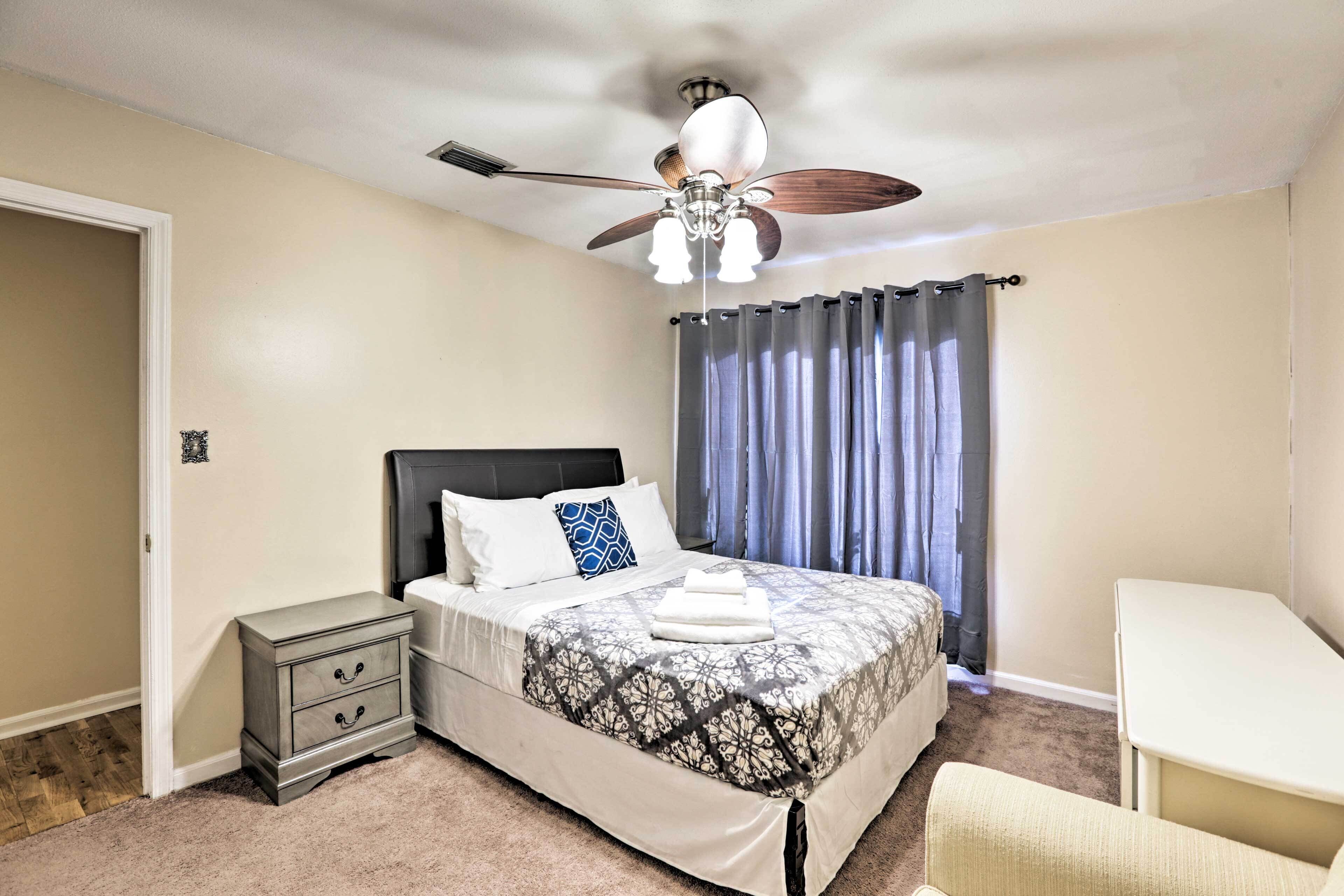 Une chambre à coucher comprenant un lit, une table de chevet, une chaise et un ventilateur de plafond.