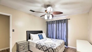 Un dormitorio con cama, mesita de noche, silla y ventilador de techo.