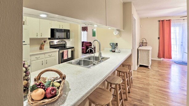 Una cocina con una isla grande, pileta de acero inoxidable y taburetes de madera.