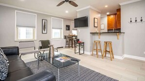 A modern living room with a glass coffee table, a leather sofa, and a ceiling fan. - Downtown Atlanta Condo with Spectacular Views (Atlanta)