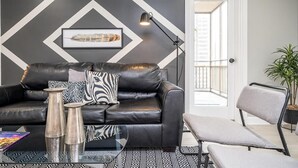A modern living room with a black leather sofa, a patterned rug, and a framed picture on the wall. - Downtown Atlanta Condo with Spectacular Views (Atlanta)