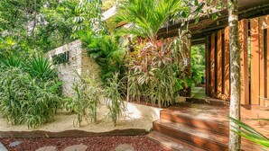 A tropical garden with a stone wall, wooden steps, and various plants. - Eco-Lifestyle Community with Magnificent Amenities  (Tulum)