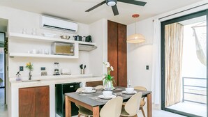 A modern kitchen with a dining area, featuring a built-in microwave, a coffee maker, and a blender on the countertop. - Eco-Lifestyle Community with Magnificent Amenities  (Tulum)