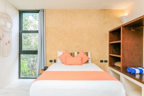 A bedroom with a large bed, a wooden wardrobe, and a view of greenery through a window. - Eco-Lifestyle Community with Magnificent Amenities  (Tulum)