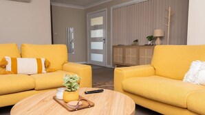 Un salon avec deux canapés jaunes, une table basse ronde et un meuble sur lequel est posée une plante.