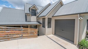 Une maison moderne avec un garage, un toit en pente et une clôture en bois.