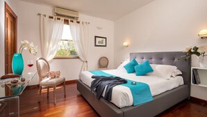Ein Schlafzimmer mit Bett, Sessel, Schreibtisch und einem Fenster mit Vorhängen.