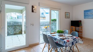 Een eetruimte met een tafel voor vier personen, een televisie en uitzicht op buiten.