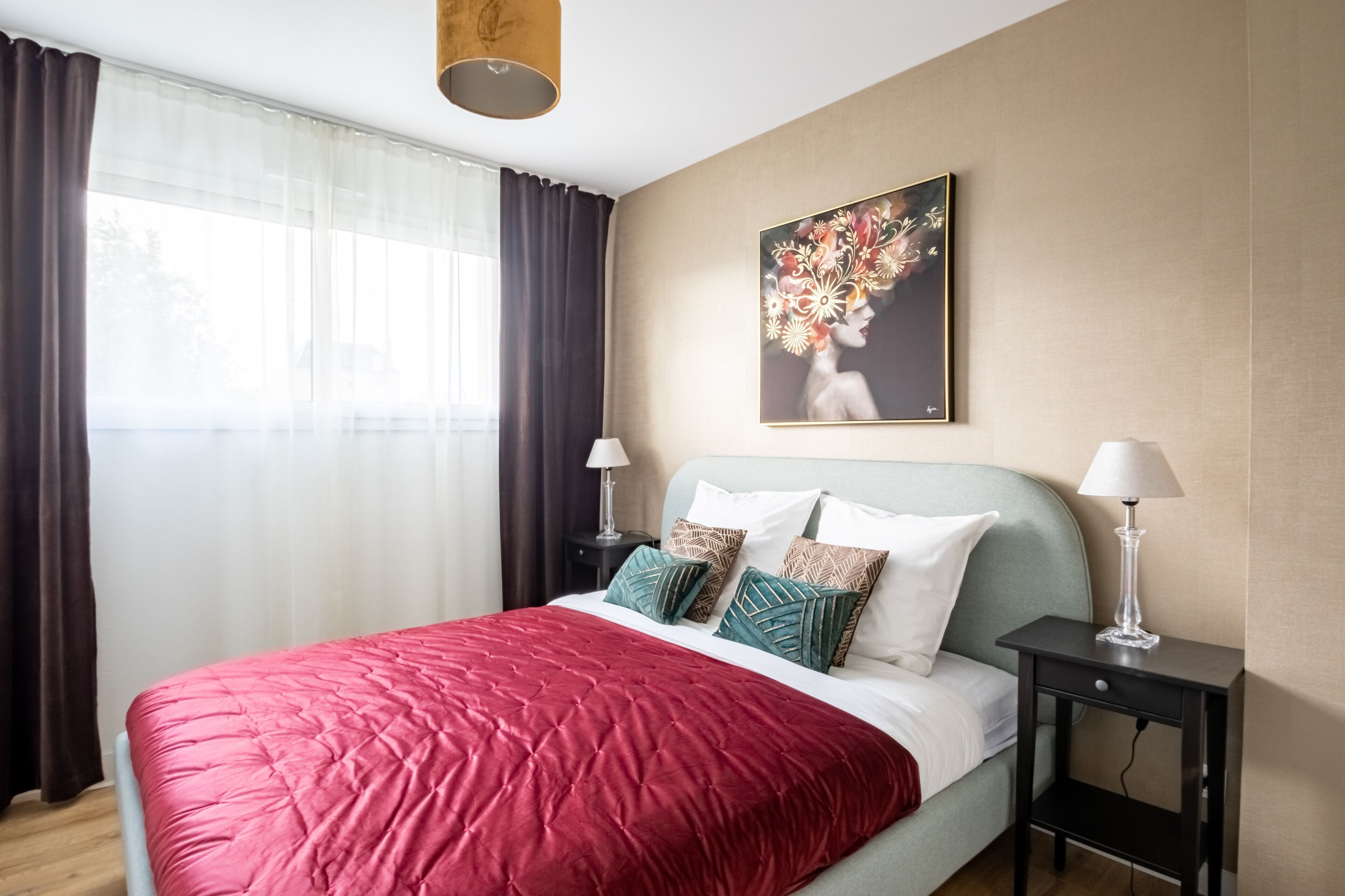 Un dormitorio ordenado con una cama grande, una mesita de noche, una lámpara y un cuadro en la pared.