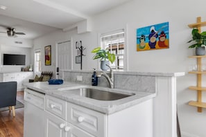 Modern kitchen with a central island, white cabinetry, and a dishwasher.