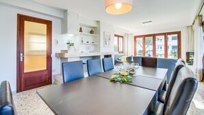 Een moderne eethoek met een grote tafel, blauwe stoelen en een hangende lamp.