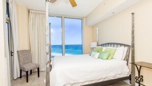 Une chambre à coucher avec un lit, une chaise, une table de chevet et une vue sur l’océan.