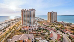 A coastal hotel complex with multiple high-rise buildings, a beach, and a parking area. - Sunrise views from your balcony! (Pensacola Beach)