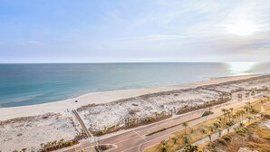 A coastal road with a beach on one side and a road on the other. - Sunrise views from your balcony! (Pensacola Beach)