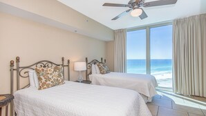 Une chambre d’hôtel avec deux lits, un ventilateur de plafond et vue sur la plage.