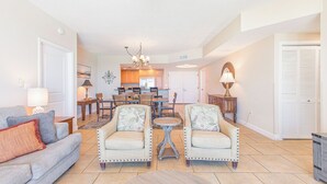 Un salon spacieux avec un canapé gris, deux fauteuils, une table basse et un coin repas doté de meubles en bois.