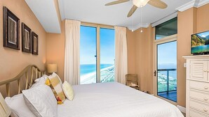 A hotel room with a large bed, a ceiling fan, a TV, and a view of the ocean. - P3-2002 2B Gulf Front*Sunset Views! (Pensacola Beach)