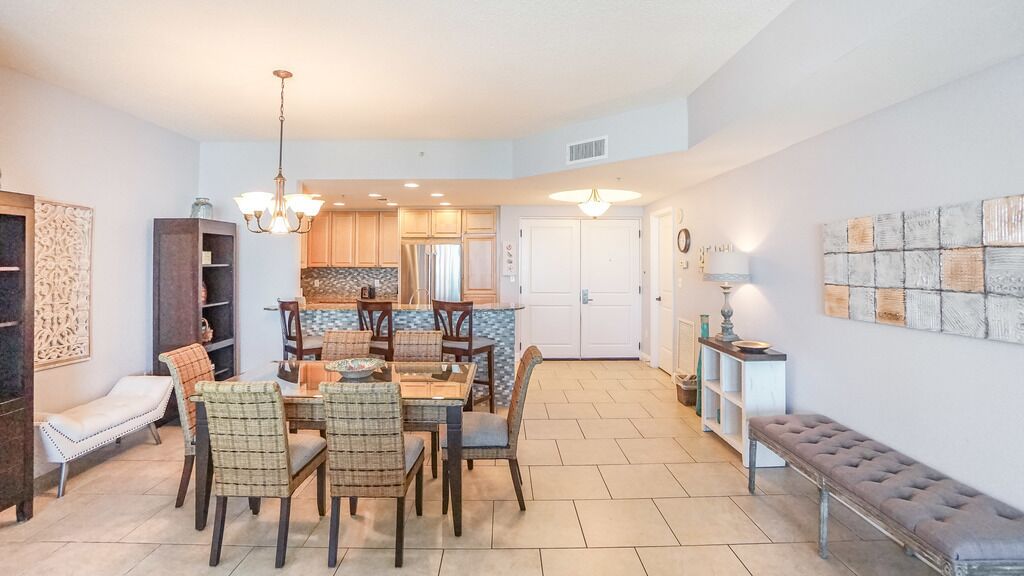 A spacious dining area with a large table and chairs, a bench, and a kitchen in the background.