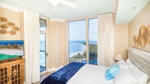 A bedroom with a large bed, a television, and a view of the ocean. - Portofino Sky Home | Sound Views | Tower 4-0803 (Pensacola Beach)
