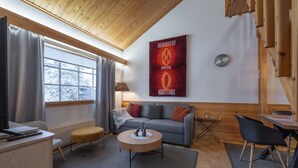A modern living room with a grey sofa, wooden coffee table, and a red tapestry on the wall. - Kuukkeli Apartments Teerenpesue E 33 (Saariselka)
