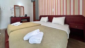 Ett hotellrum med två sängar, ett träbord vid sängen, en spegel och en randig vägg.