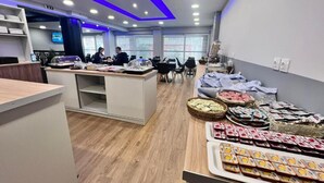 En modern hotellobby med en receptionsdisk, en sittgrupp och ett område där mat och dryck exponeras.
