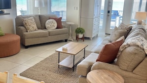 A modern living room with a sofa, coffee table, and a dining area with a table and chairs. - "Sandy Toes" ON THE SAND! (Destin)