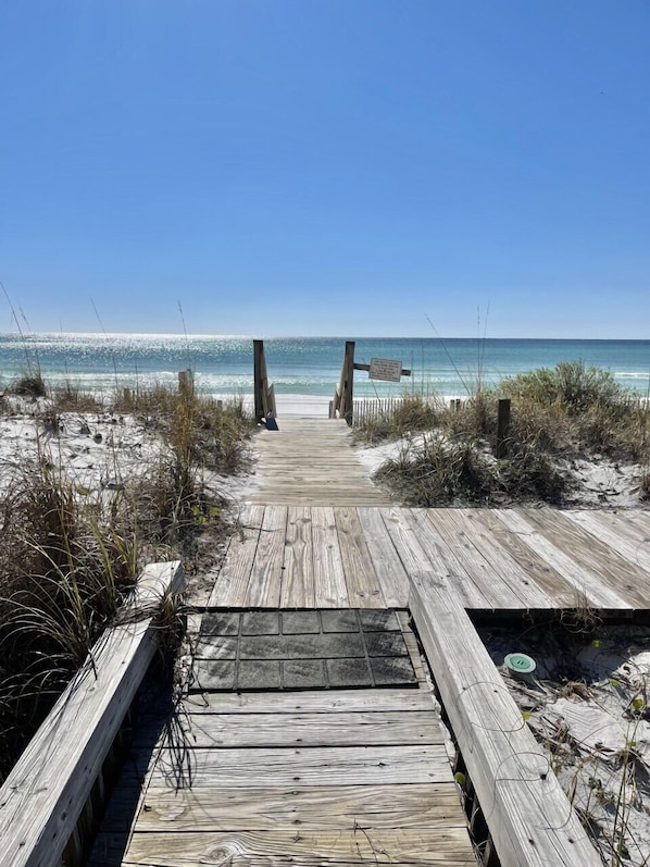A wooden boardwalk leading to a beach with clear skies.