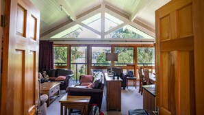 A spacious living area with a high ceiling, large windows, and a cozy seating arrangement.