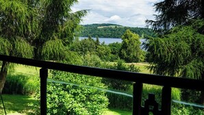 A scenic view from a balcony overlooking a lake, surrounded by lush greenery and trees.