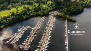 An aerial view of a marina with numerous boats docked in a structured layout, surrounded by lush greenery and a river.
