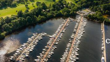 An aerial view of a marina with numerous boats docked in a structured layout, surrounded by lush greenery and a river.