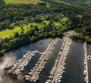 An aerial view of a marina with numerous boats docked in a structured layout, surrounded by lush greenery and a river. - 2 days in London & Xmas week at Scotland’s Cameron House (Dec 20-29) (Loch Lomond, West Dunbartonshire, Scotland)